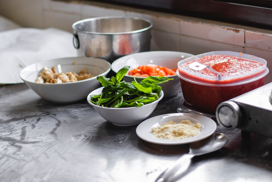 An arrangement of fresh ingredients including basil, tomatoes, and cheese on a kitchen counter for a delicious meal.