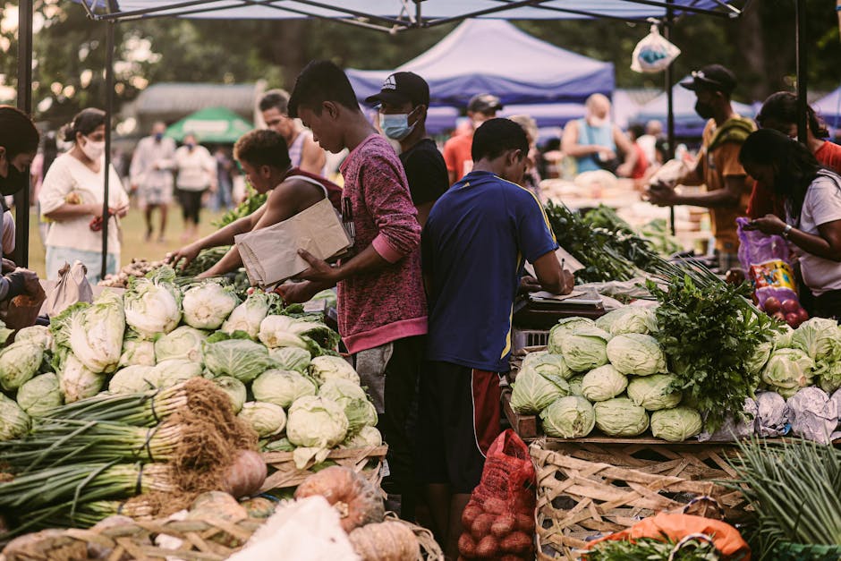 Vibrant farmers market scene with diverse people and fresh vegetables on a sunny day.