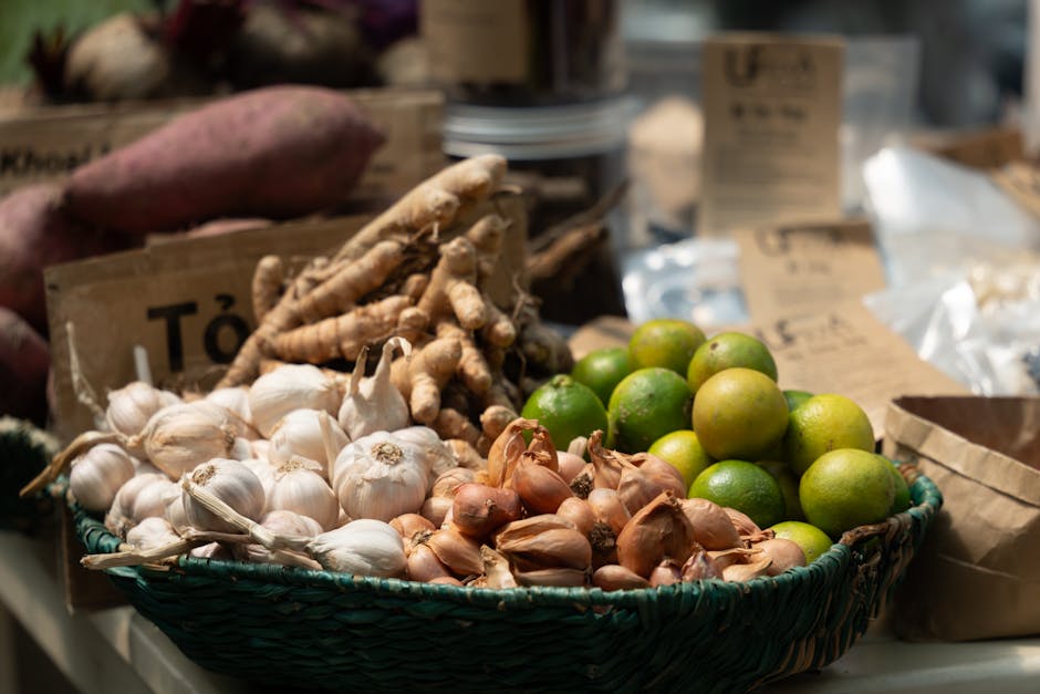 Vibrant assortment of garlic, limes, ginger, and shallots in a market setting.