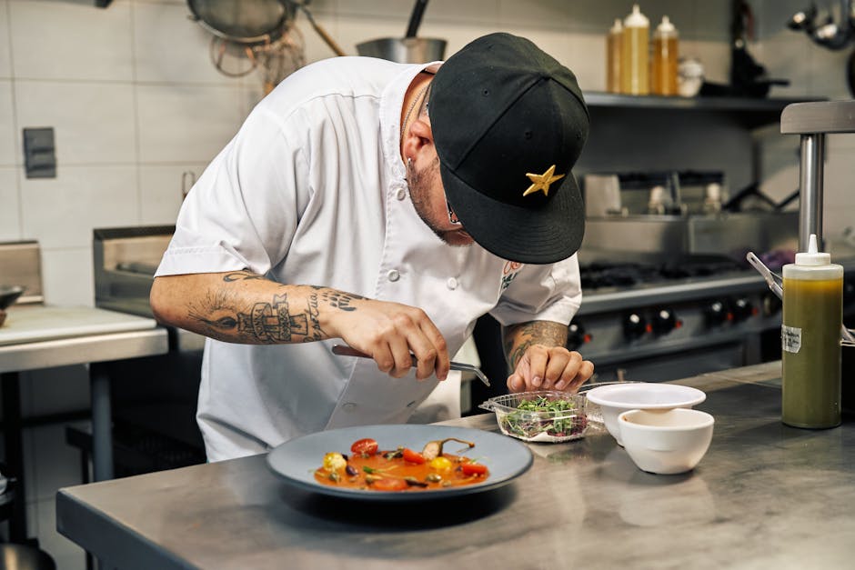 Chef meticulously plating food in a modern kitchen, showcasing culinary artistry.