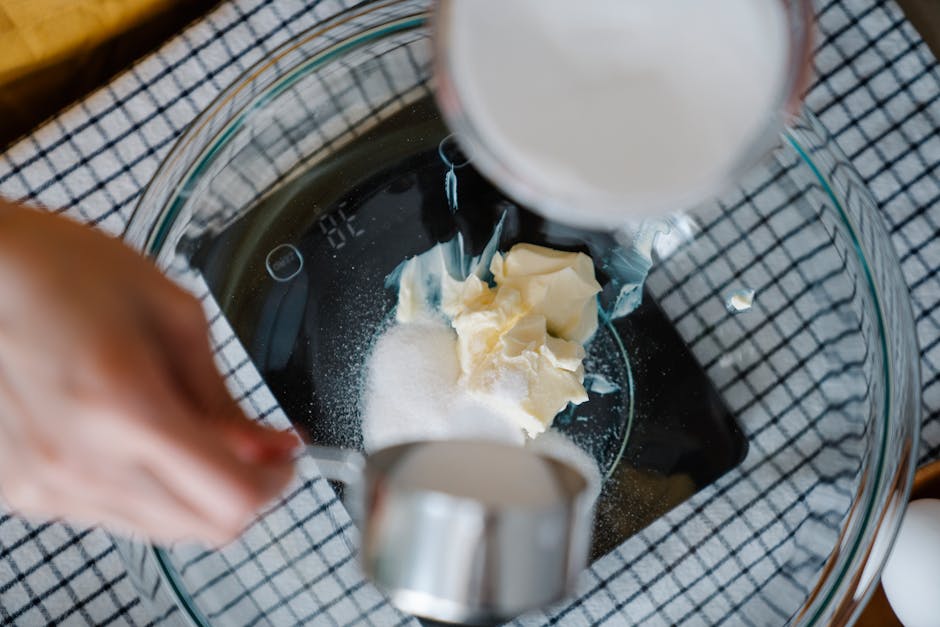 Hands measuring sugar and butter in a bowl for a recipe. Perfect for baking enthusiasts.