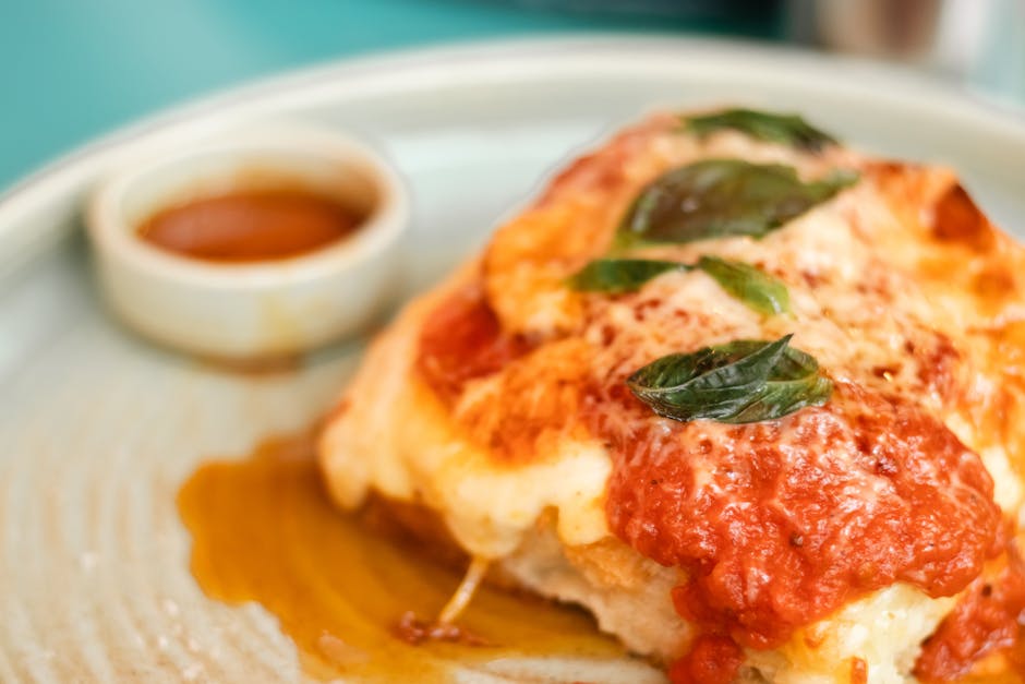 Close-up of a mouthwatering Italian lasagna topped with fresh basil leaves on a white plate.