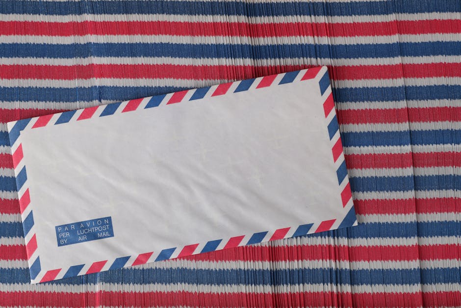 Flat lay of an airmail envelope on a red, white, and blue striped surface.