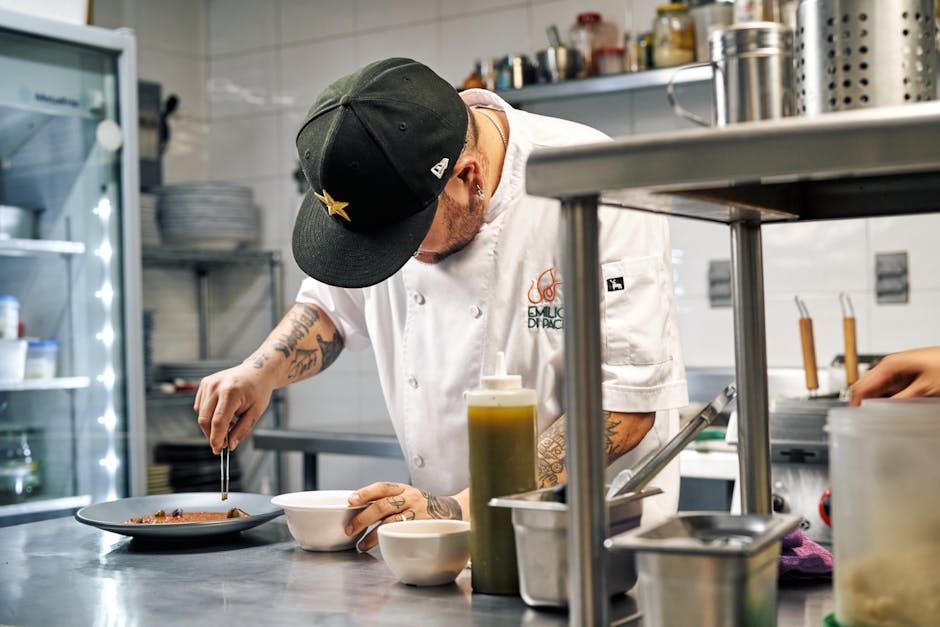 Chef in a professional kitchen carefully plating a dish with precision and artistry.
